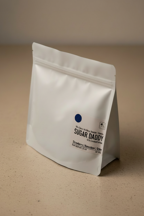 Sugar Daddy V2.0 Limited Edition coffee bag — white matte packaging standing upright with navy blue dot and tasting notes of strawberry, honeydew, and grape